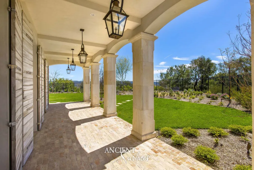 Antique limestone columns carrying the arches of a villa loggia above antique brick paving