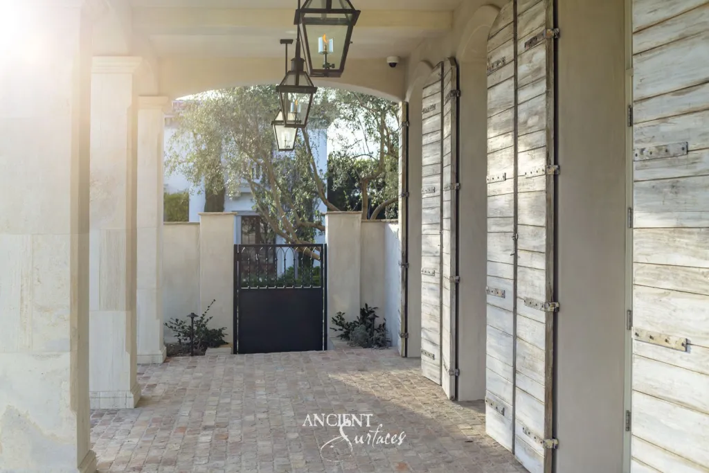 Antique brick paving running the length of an exterior corridor to an iron garden gate