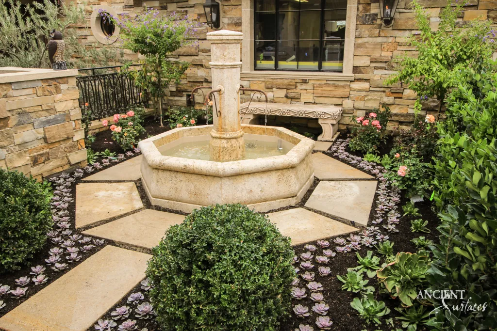 Octagonal antique limestone fountain with a carved central column standing on reclaimed stone paving