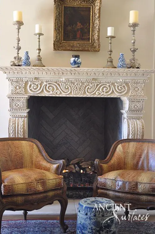 Limestone mantel frieze carved by hand with running scrollwork and rosettes above a black herringbone firebox